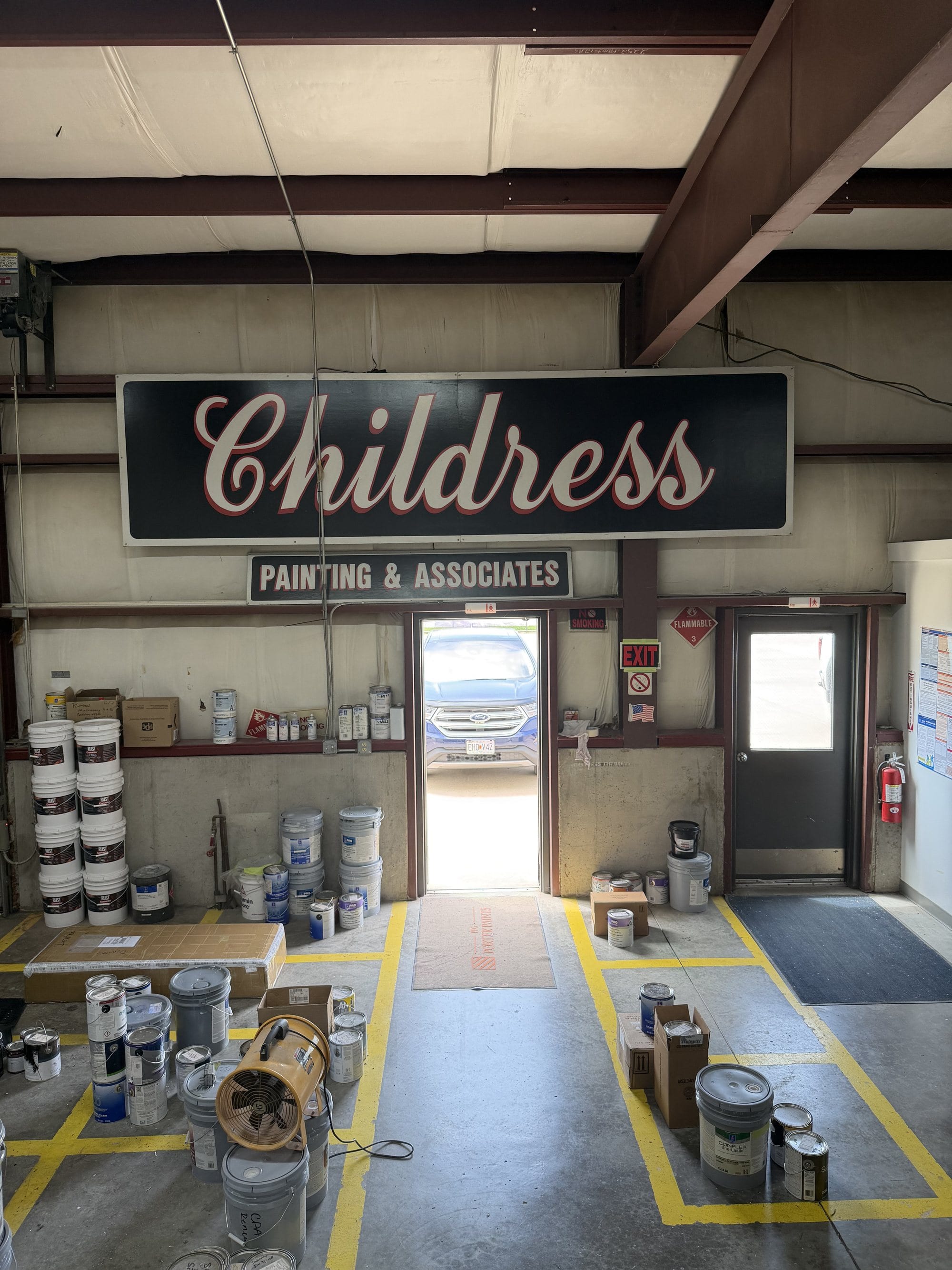 Inside the Childress Painting shop, with the company sign above the door and staged coating materials